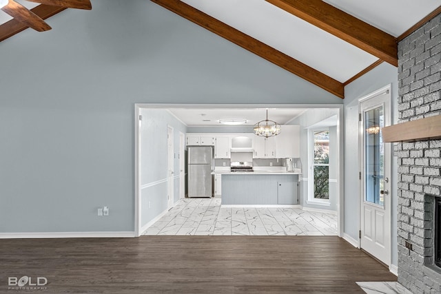 kitchen with beam ceiling, appliances with stainless steel finishes, pendant lighting, a fireplace, and white cabinets