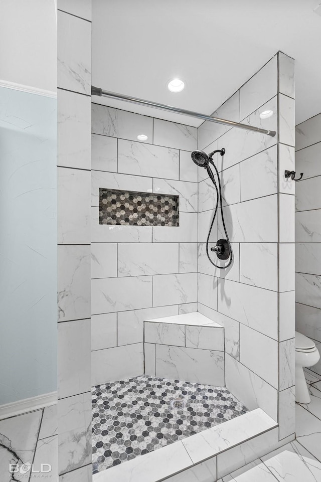 bathroom with tiled shower and toilet