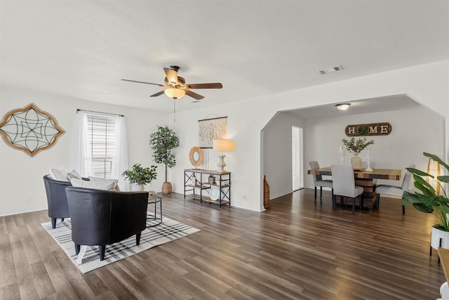 living room with a textured ceiling, dark wood-type flooring, and ceiling fan