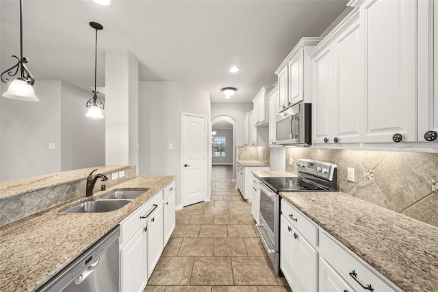 kitchen with sink, tasteful backsplash, pendant lighting, stainless steel appliances, and white cabinets