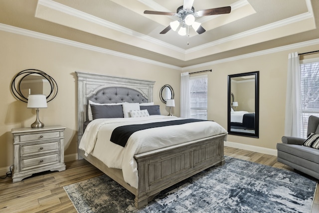 bedroom with crown molding, a raised ceiling, and light hardwood / wood-style floors