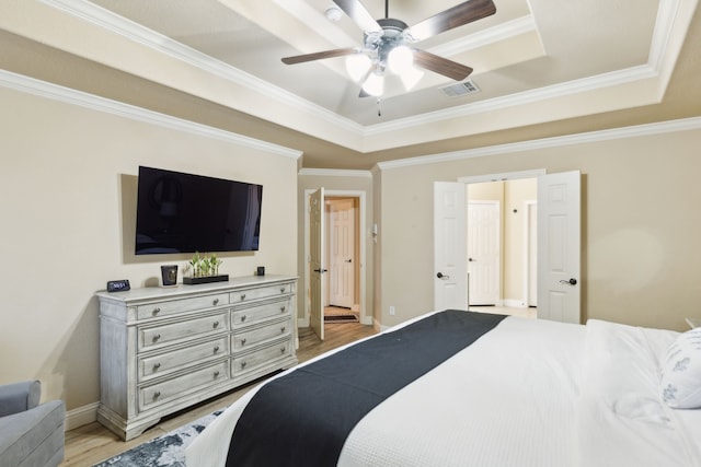 bedroom with a raised ceiling, ornamental molding, ceiling fan, and light hardwood / wood-style floors