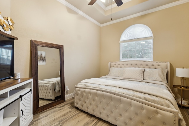 bedroom featuring ornamental molding, a raised ceiling, ceiling fan, and light wood-type flooring