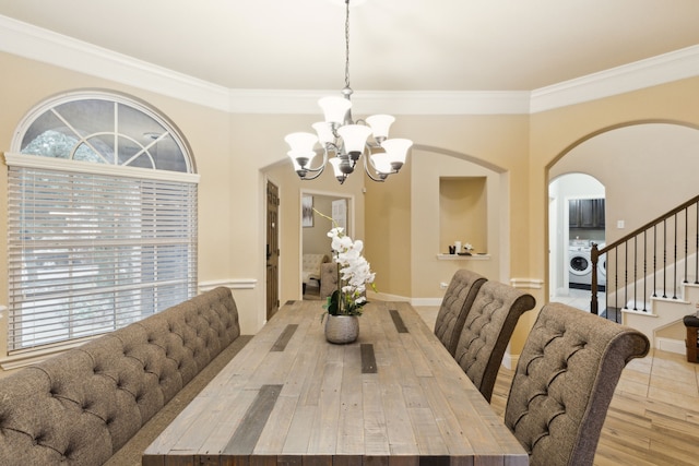 dining room with crown molding, washer / dryer, light wood-type flooring, and a chandelier