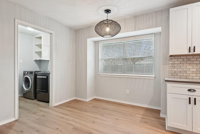 kitchen featuring white cabinetry, decorative light fixtures, washer and dryer, and light wood-type flooring