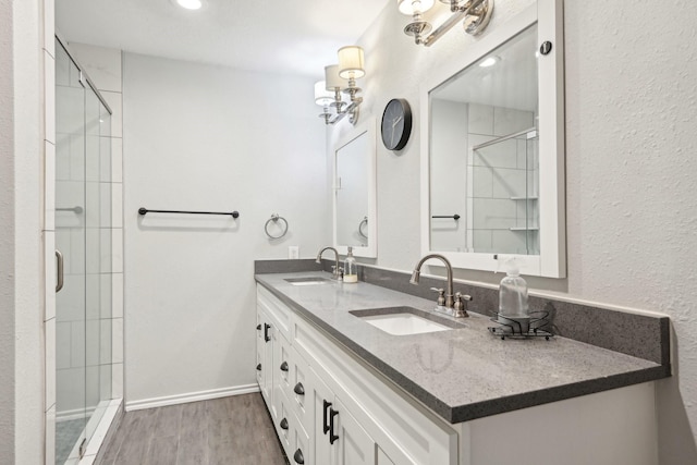 bathroom featuring wood-type flooring, tiled shower, and vanity