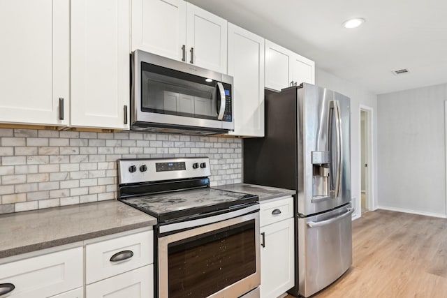 kitchen with white cabinetry, appliances with stainless steel finishes, light hardwood / wood-style floors, and backsplash