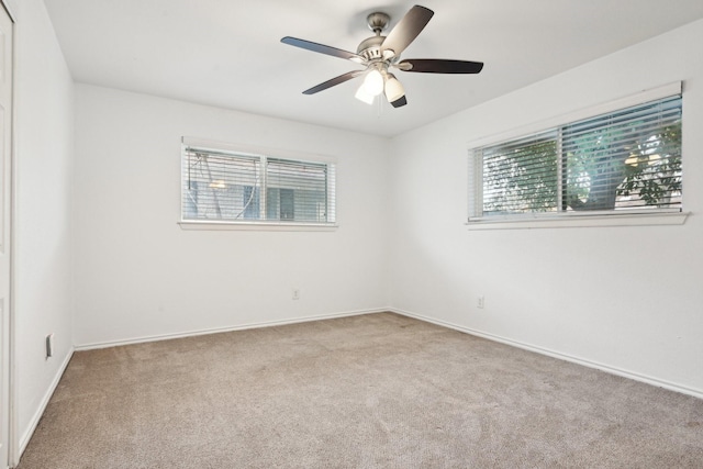 empty room with ceiling fan, light colored carpet, and plenty of natural light