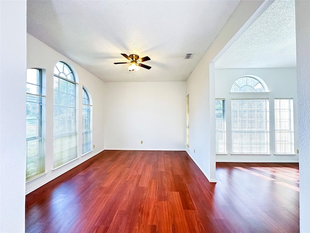 unfurnished room with ceiling fan, dark hardwood / wood-style floors, and a textured ceiling