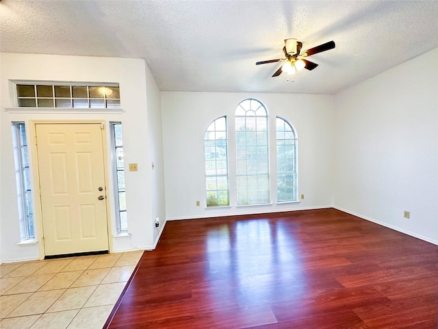 foyer with wood-type flooring, ceiling fan, and a textured ceiling