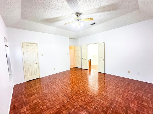 empty room featuring a textured ceiling, parquet flooring, and ceiling fan