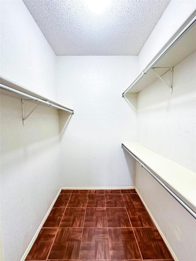 spacious closet featuring dark parquet flooring