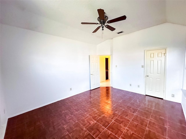 empty room with vaulted ceiling, ceiling fan, and dark parquet floors