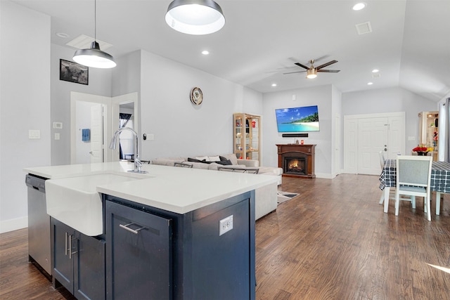 kitchen with hanging light fixtures, an island with sink, dishwasher, and dark hardwood / wood-style flooring