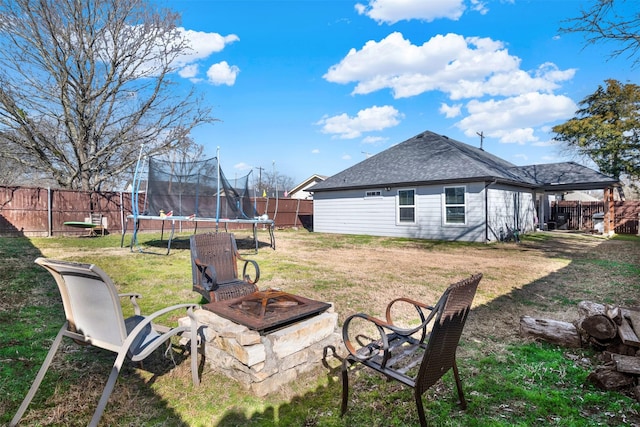 view of yard with a trampoline and a fire pit