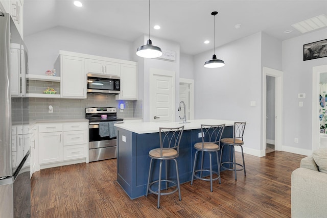 kitchen with stainless steel appliances, a kitchen island with sink, white cabinets, and decorative light fixtures