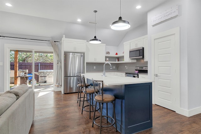 kitchen featuring pendant lighting, lofted ceiling, appliances with stainless steel finishes, an island with sink, and white cabinets