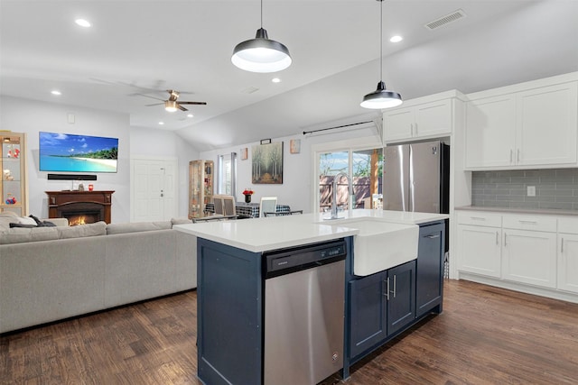 kitchen featuring sink, white cabinetry, decorative light fixtures, appliances with stainless steel finishes, and a kitchen island with sink