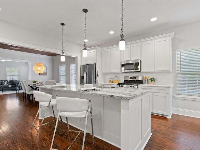 kitchen with appliances with stainless steel finishes, a kitchen island with sink, and white cabinets