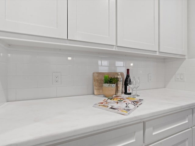 interior details with white cabinetry, bar area, and decorative backsplash