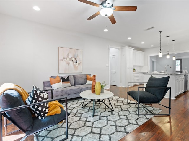 living room featuring dark wood-type flooring, sink, and ceiling fan