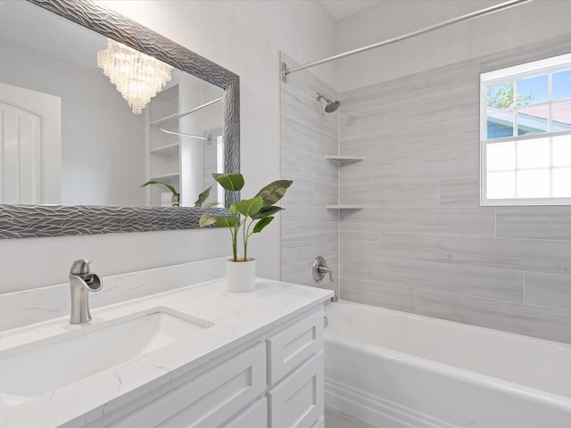 bathroom featuring an inviting chandelier, vanity, and tiled shower / bath combo