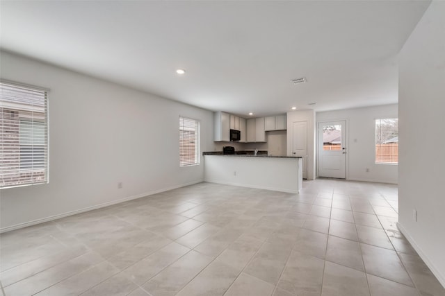 unfurnished living room with light tile patterned flooring and a healthy amount of sunlight