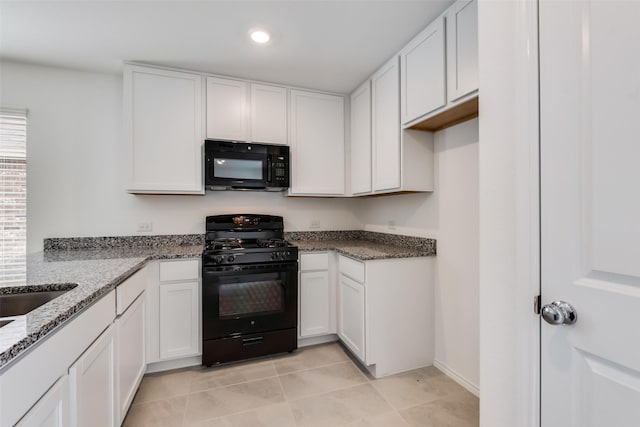 kitchen featuring light tile patterned flooring, white cabinetry, black appliances, and stone countertops