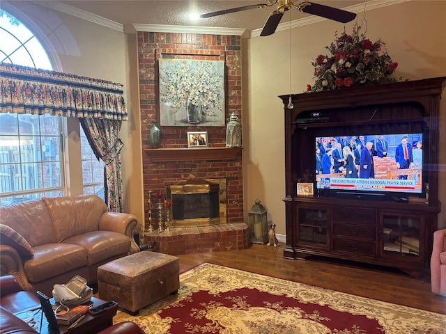 living room with crown molding, wood-type flooring, ceiling fan, and a fireplace