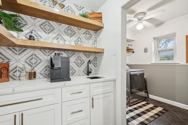 bar with sink, light stone counters, tasteful backsplash, washer and dryer, and white cabinets