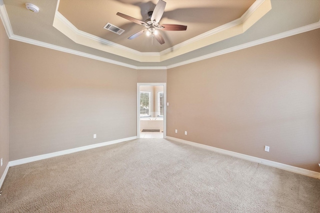 carpeted empty room with visible vents, crown molding, baseboards, a raised ceiling, and a ceiling fan