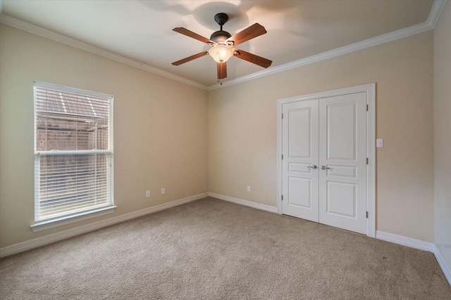 empty room with ceiling fan, carpet flooring, baseboards, and ornamental molding