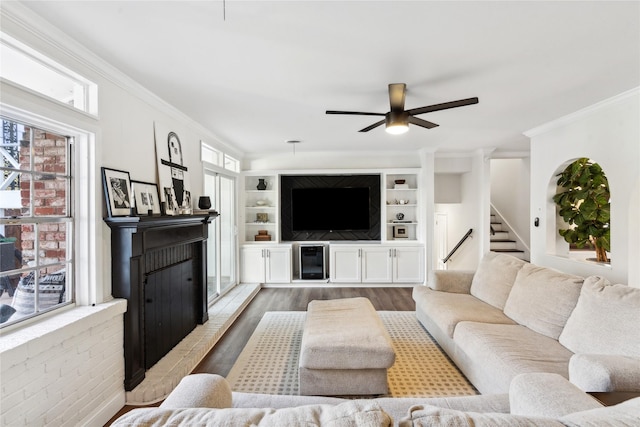 living room featuring hardwood / wood-style flooring, ornamental molding, built in features, and ceiling fan