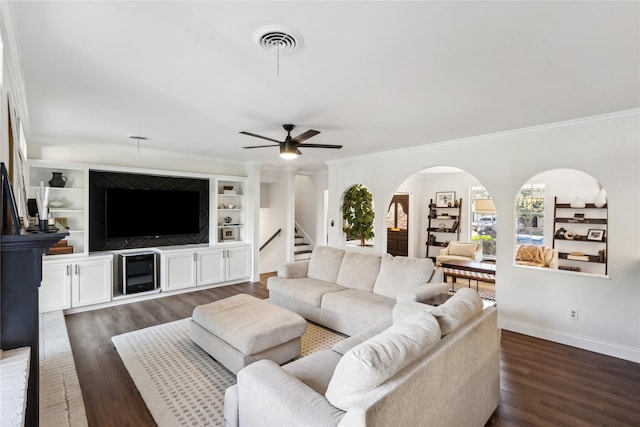 living room featuring built in shelves, ornamental molding, dark hardwood / wood-style floors, and ceiling fan