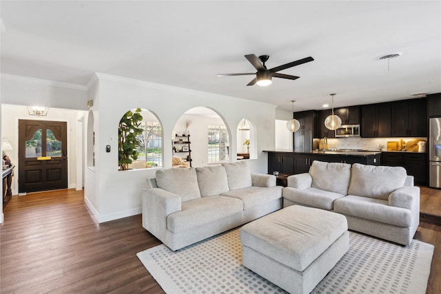 living room with ornamental molding, dark hardwood / wood-style floors, and ceiling fan