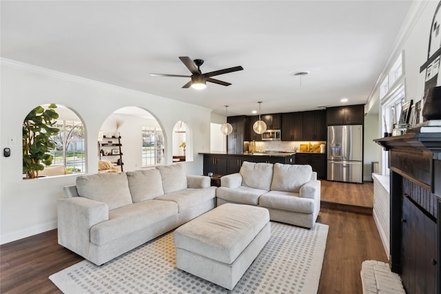 living room featuring dark wood-type flooring, ceiling fan, and crown molding