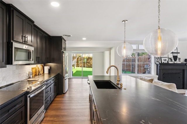 kitchen featuring sink, appliances with stainless steel finishes, hanging light fixtures, dark brown cabinetry, and decorative backsplash