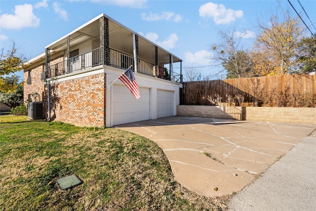 view of side of property featuring a garage, a balcony, a yard, and central AC unit