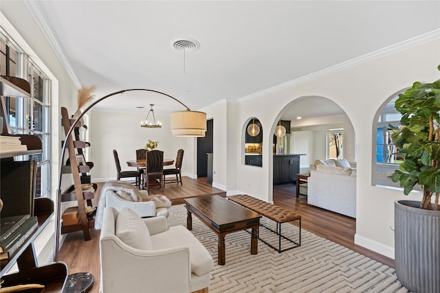 living room featuring hardwood / wood-style floors, crown molding, and a notable chandelier