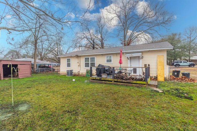 back of property with a lawn, fence, and central AC