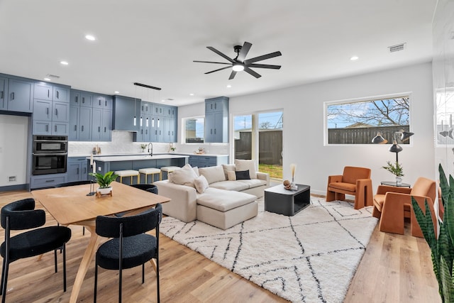 living room featuring ceiling fan, sink, and light hardwood / wood-style floors