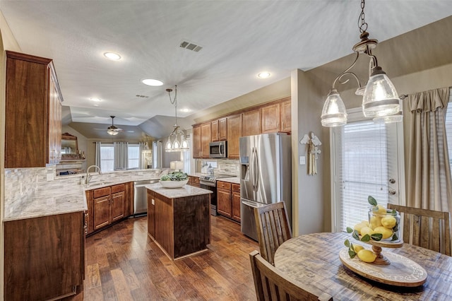 kitchen with a center island, vaulted ceiling, kitchen peninsula, pendant lighting, and stainless steel appliances