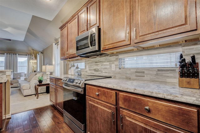 kitchen featuring lofted ceiling, stainless steel appliances, dark hardwood / wood-style floors, light stone countertops, and decorative backsplash