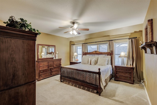 bedroom featuring multiple windows, light colored carpet, a textured ceiling, and ceiling fan