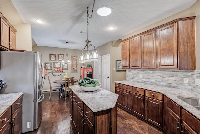 kitchen featuring hanging light fixtures, dark hardwood / wood-style floors, backsplash, and stainless steel refrigerator