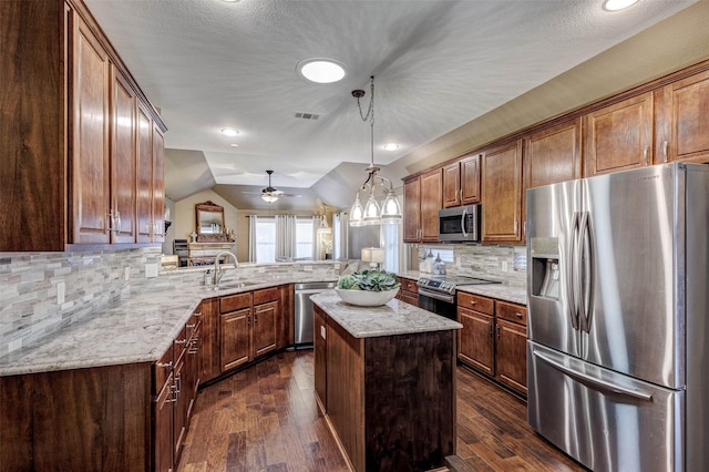 kitchen featuring a kitchen island, appliances with stainless steel finishes, sink, hanging light fixtures, and kitchen peninsula