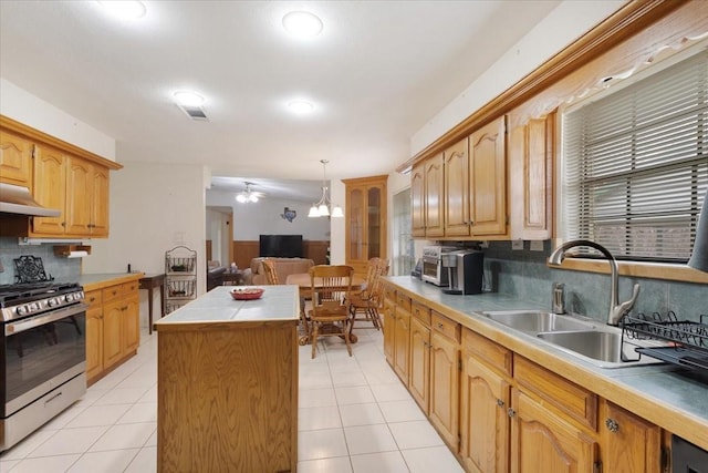 kitchen featuring a kitchen island, a sink, under cabinet range hood, stainless steel range with gas cooktop, and backsplash