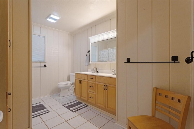 full bathroom featuring toilet, double vanity, a sink, and tile patterned floors