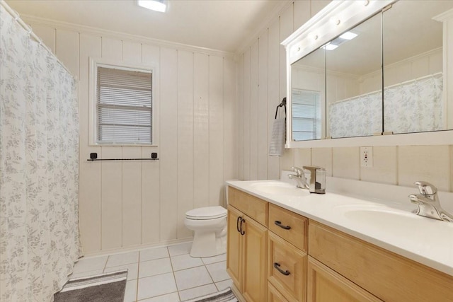 bathroom with crown molding, a sink, toilet, and tile patterned floors