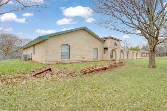 exterior space featuring a lawn, central AC, and brick siding